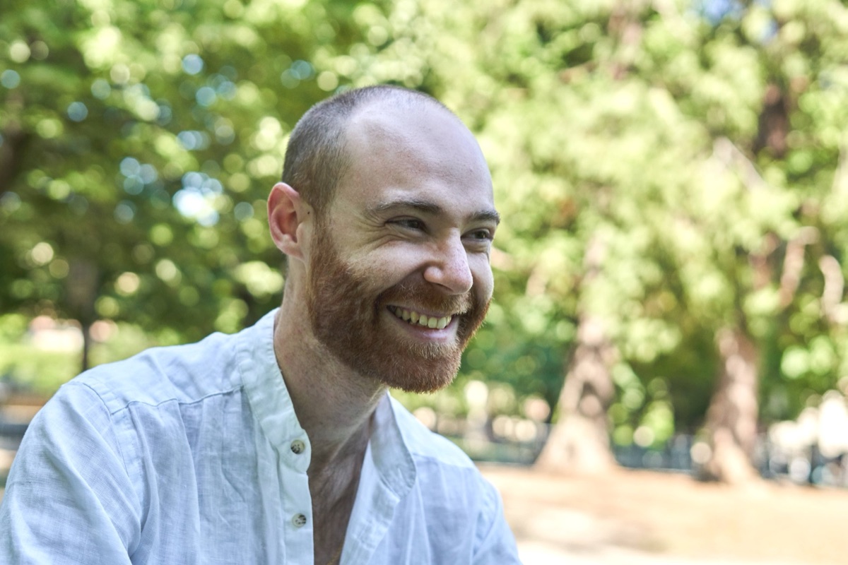 Portrait of Emmanuel Bruno, smiling, in a park